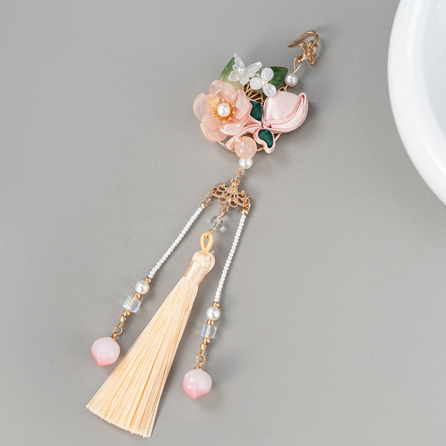 peach blossom Hanfu brooch with tassel detail displayed on fabric