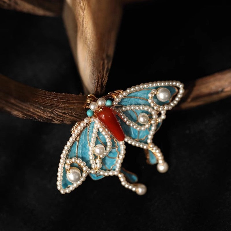 butterfly statement brooch with pearl drop detail displayed on fabric