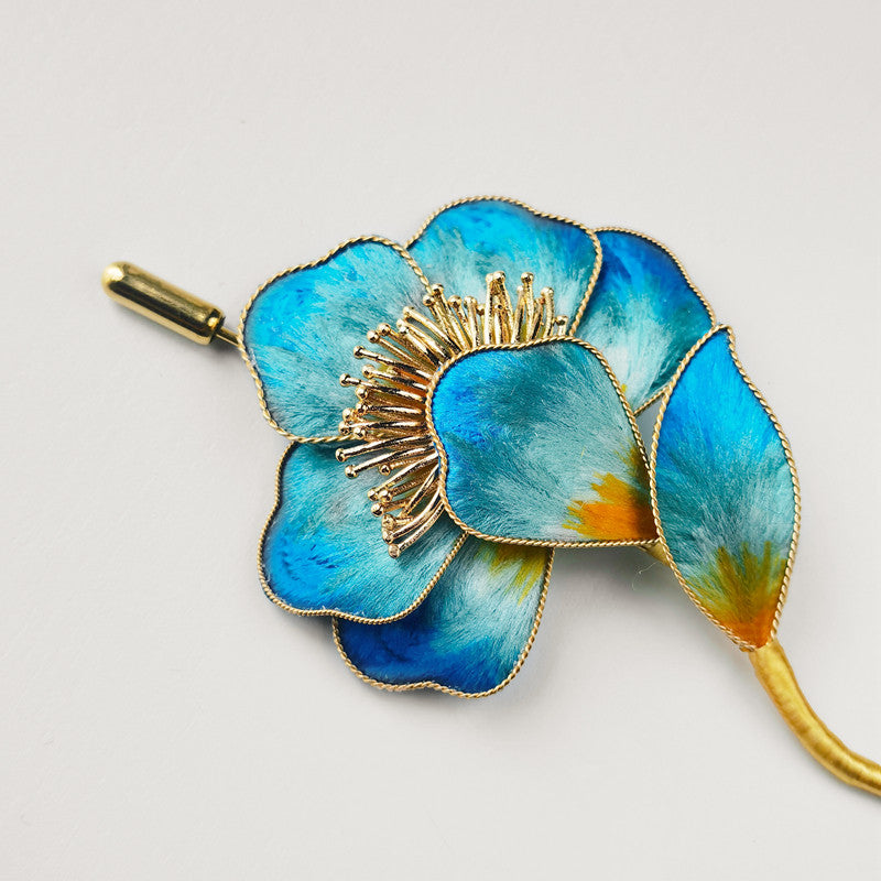 Close-up of delicate petal detail and pearl-like center on blue brooch