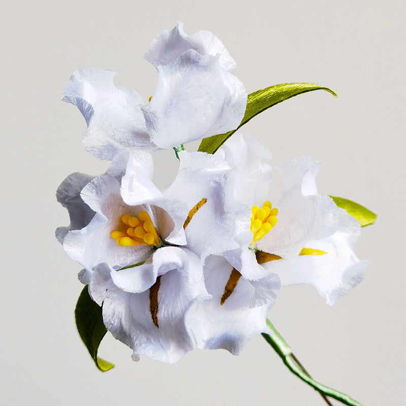 white lily brooch pin on a wedding guest dress displayed on fabric