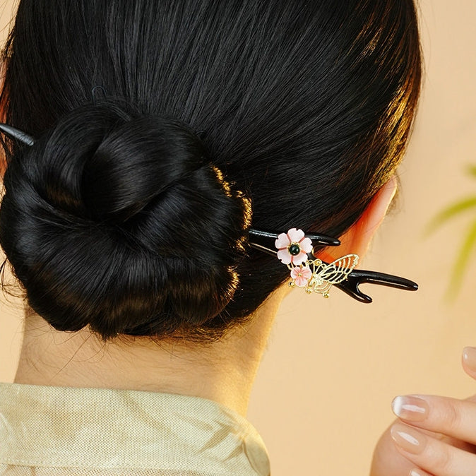 Model wears a delicate black and pink stick tucked through bun
