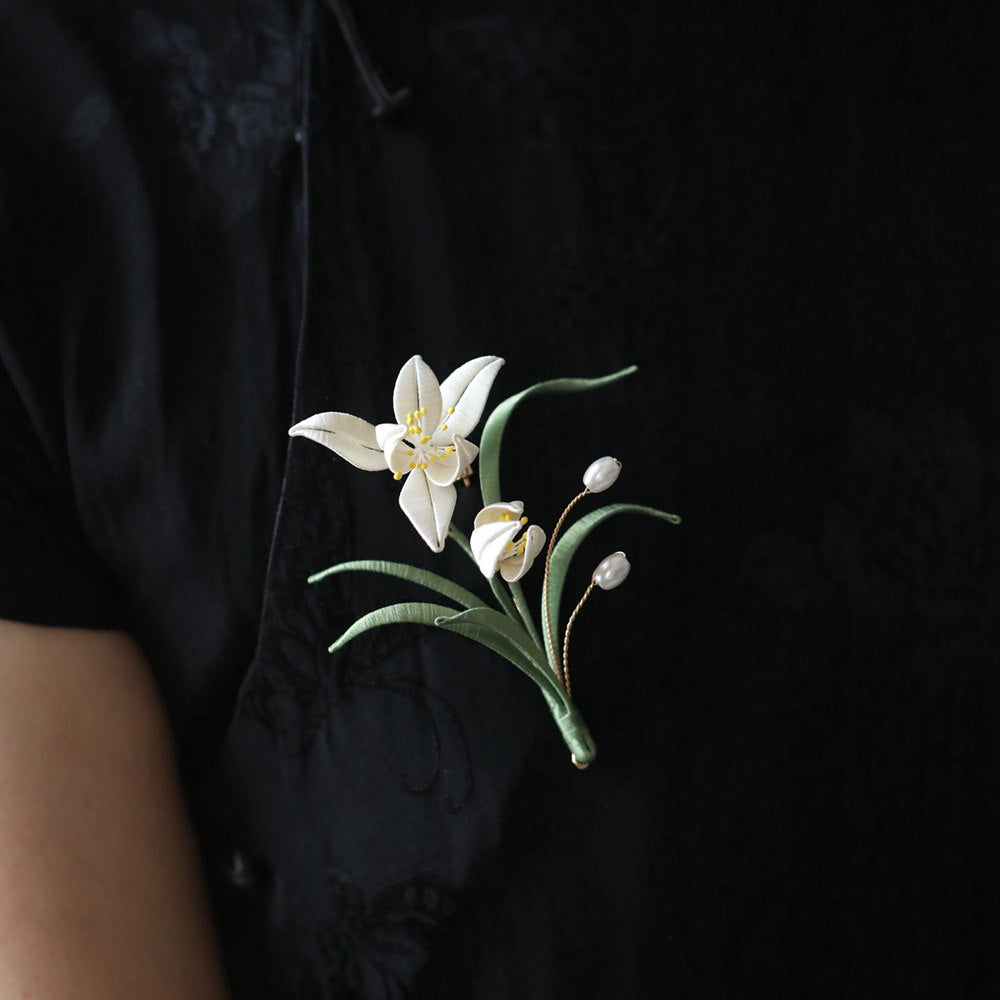 minimal orchid brooch pin styled on a cardigan displayed on fabric