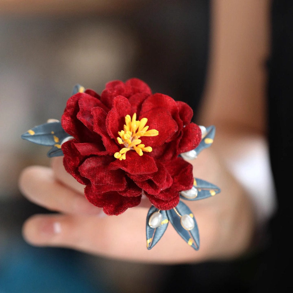 red camellia bridal brooch pin on a dress displayed on fabric