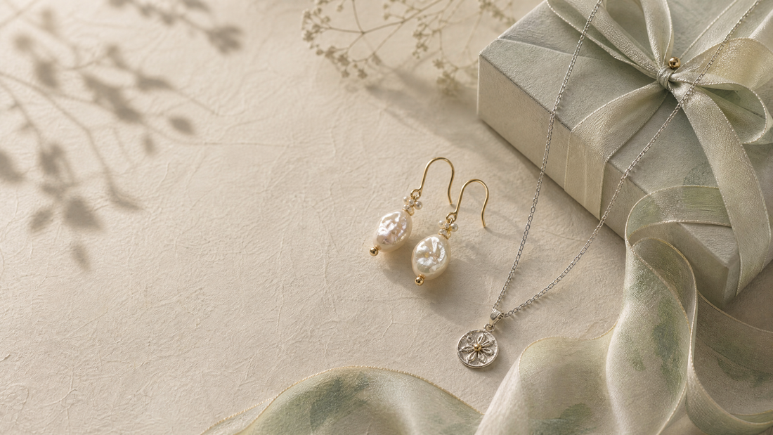 Baroque pearl earrings and a sterling-silver necklace beside a silk-wrapped jewelry gift box