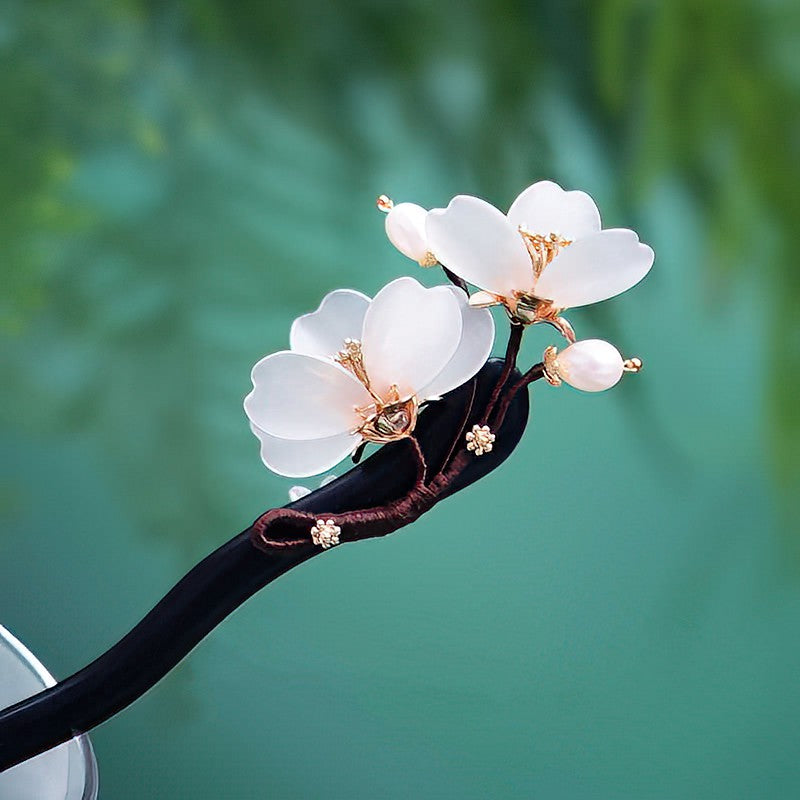 Model securing a low bun with floral hair stick, showing placement and elegant finish