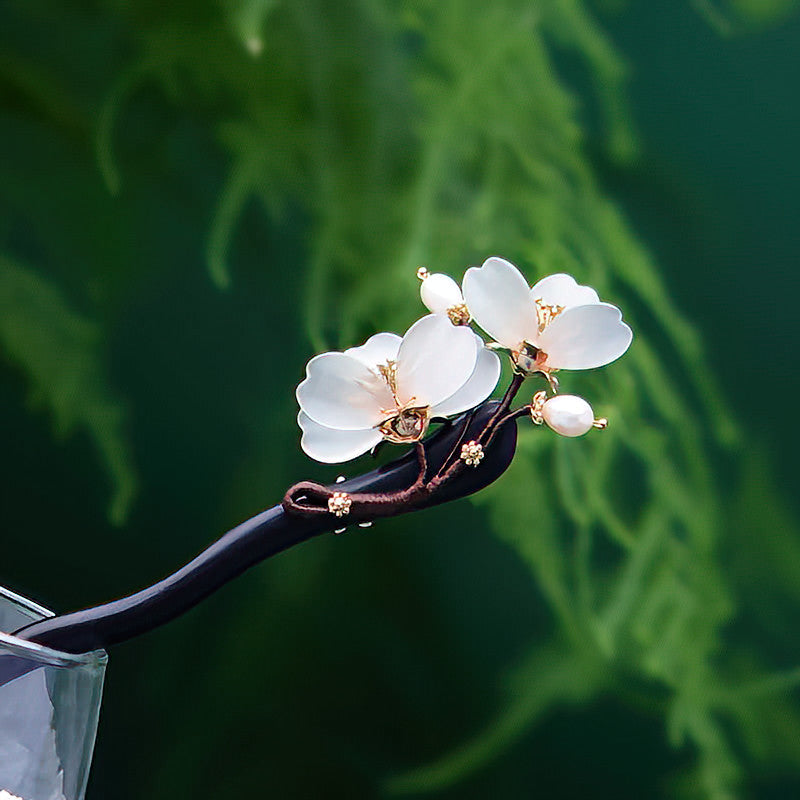 Close-up of painted petals and metal accents on a floral hair stick, soft golden tones