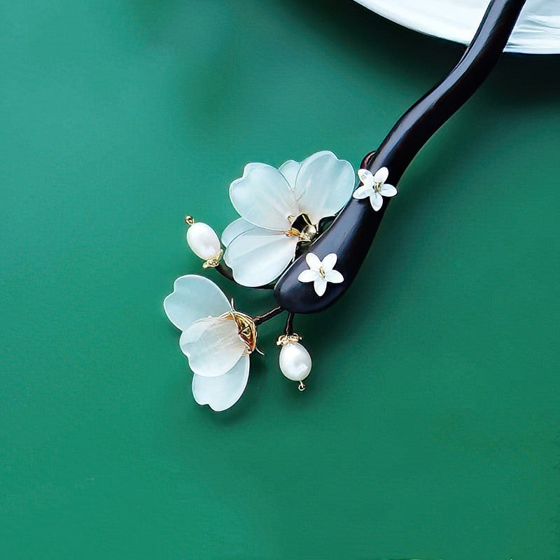 Side view of hair stick resting beside a styled bun, highlighting curved prongs and floral cap