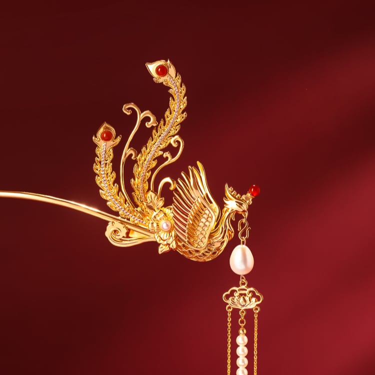 Gold-toned hair pin with crimson tassel placed across a bun on ivory fabric