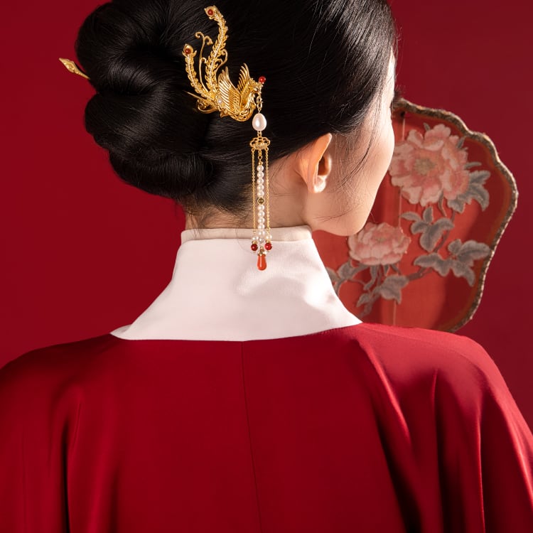 Styled in a low bridal bun, accenting soft waves and veil edge