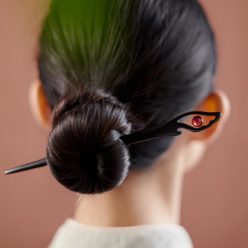 Side view showing stick securing low chignon with delicate floral accent