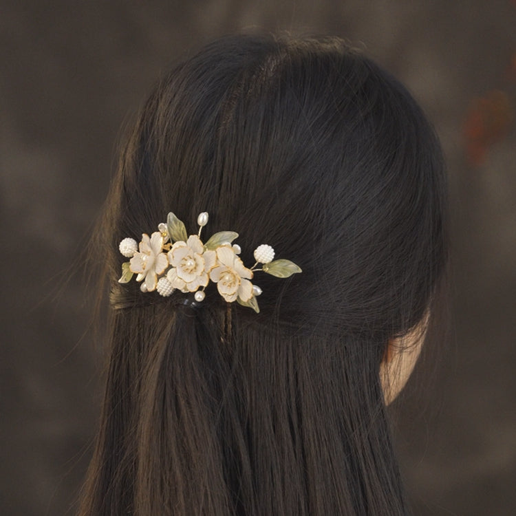Three-quarter angle showing warm gold petal detail, gentle shine, worn with half-up style