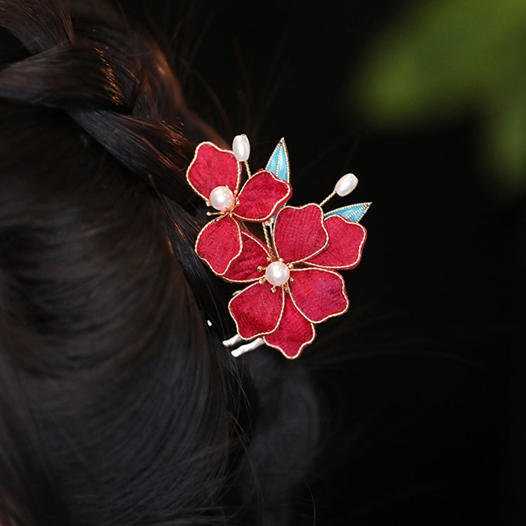 Two sticks crossed at back of bun, subtle floral detail visible against hair