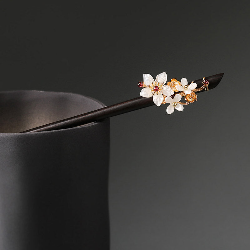 Warm brown hair stick with carved floral head resting on folded silk cloth