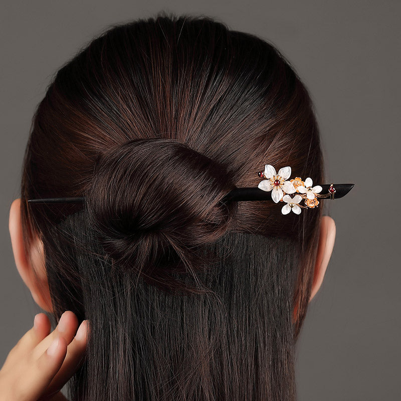 Styled through a low bun with delicate tendrils framing the nape