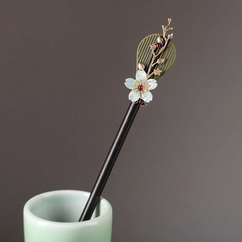 Dark wooden hair stick with carved floral motif set diagonally in bun.