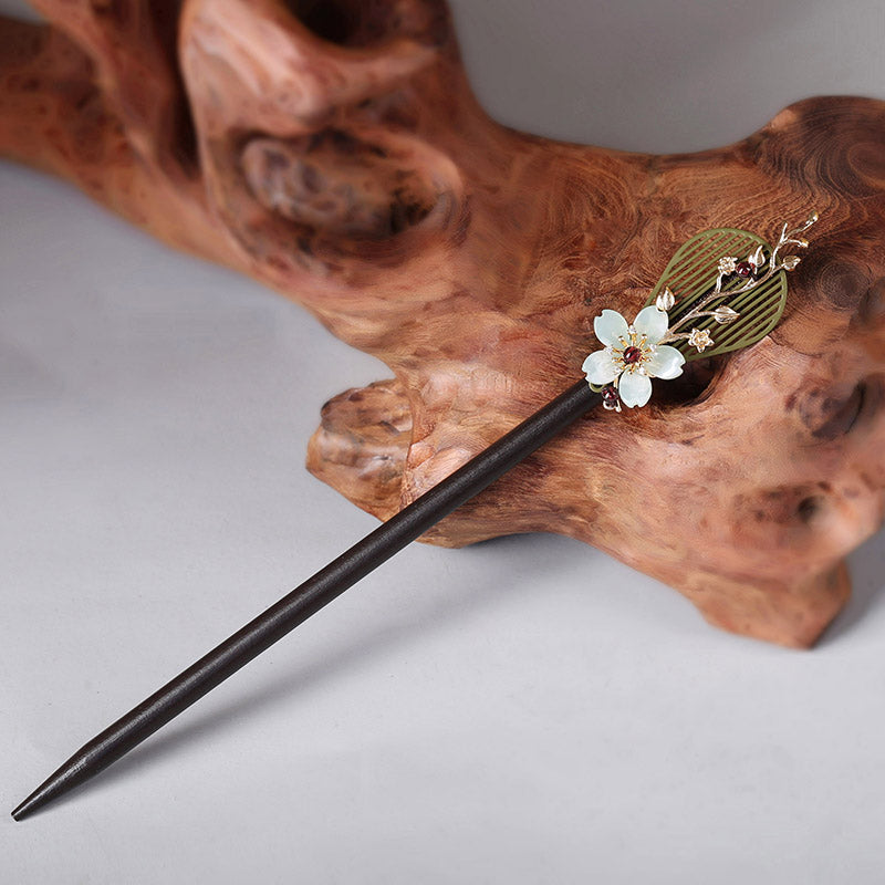 Two hair sticks crossed through a loose low bun, gentle sheen.