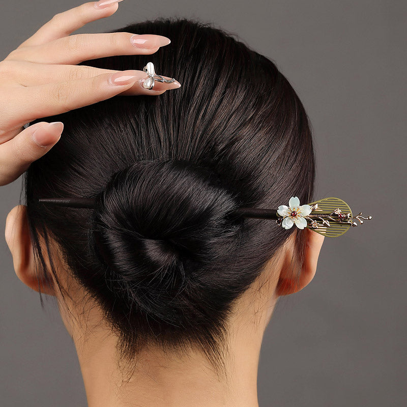 Model wearing stick horizontally across a sculpted updo, soft lighting.
