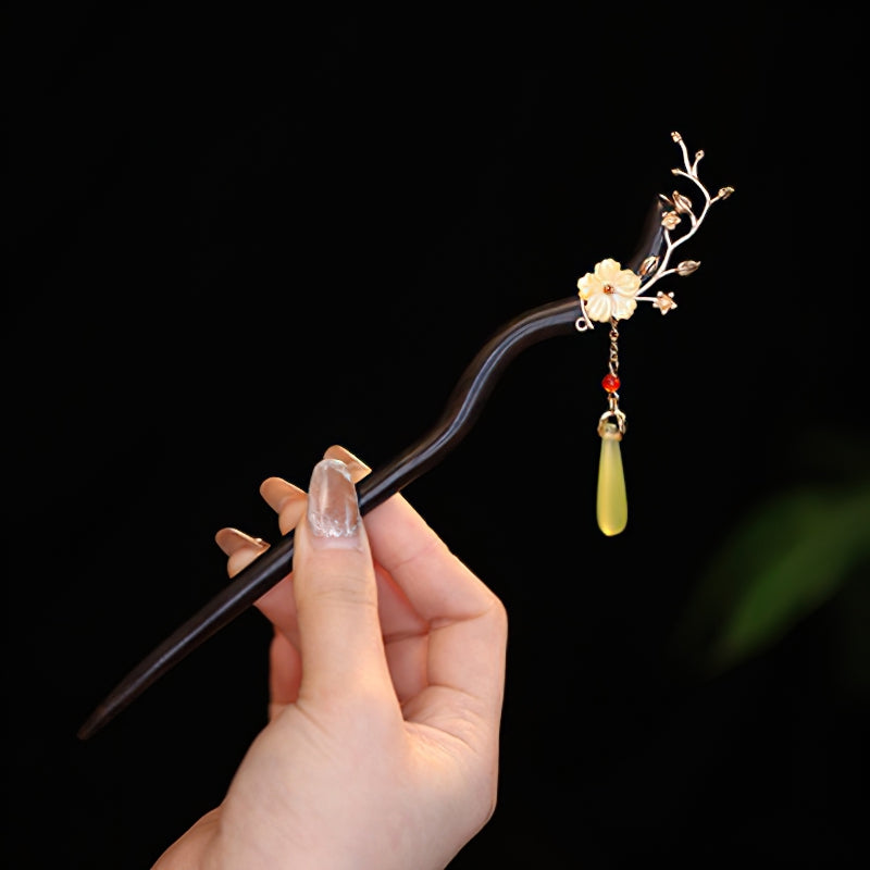 Dark wood-look stick with carved floral motif tucked into a low bun
