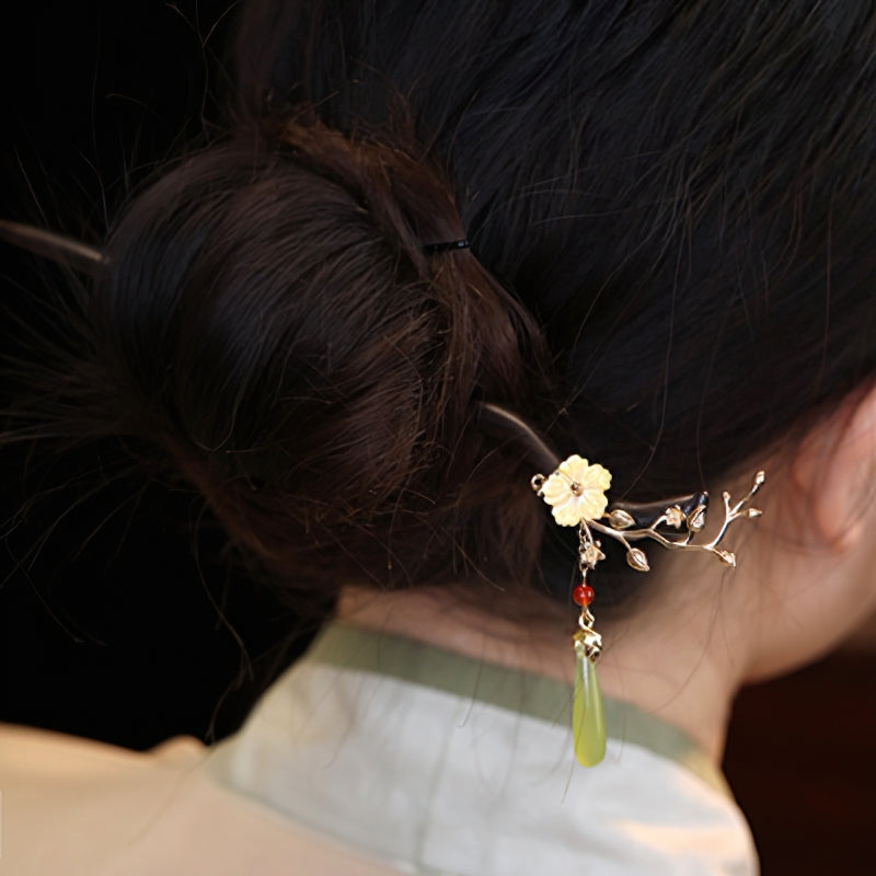 Model wearing a single floral hair stick holding a chic updo
