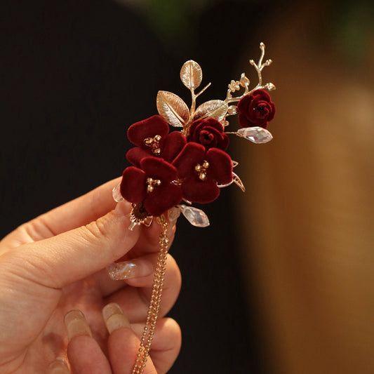 Close-up of a red camellia blossom mounted on a slender stick near a bun