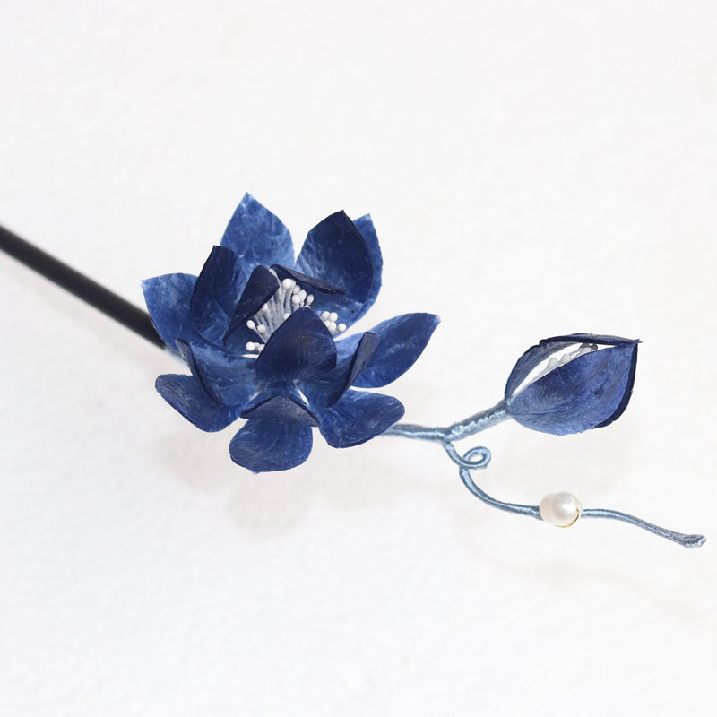 Warm wood-toned hair stick with carved lotus accent resting in low bun
