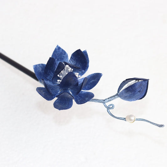 Warm wood-toned hair stick with carved lotus accent resting in low bun