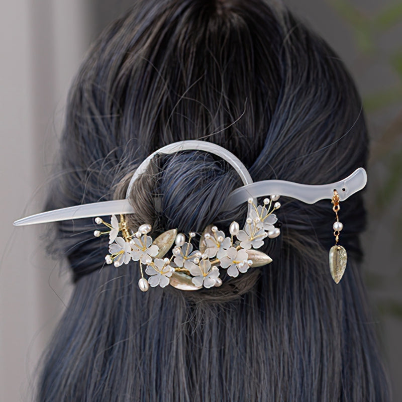 Close-up of floral headpiece detail with wrapped stick against light background