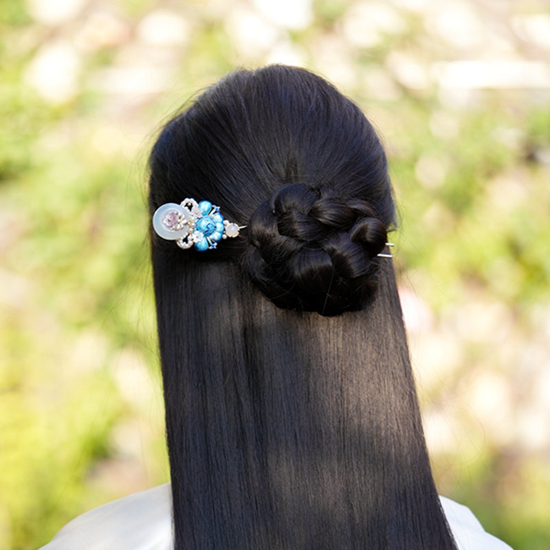 Side view showing green-toned blossom accent attached to a slim hair stick