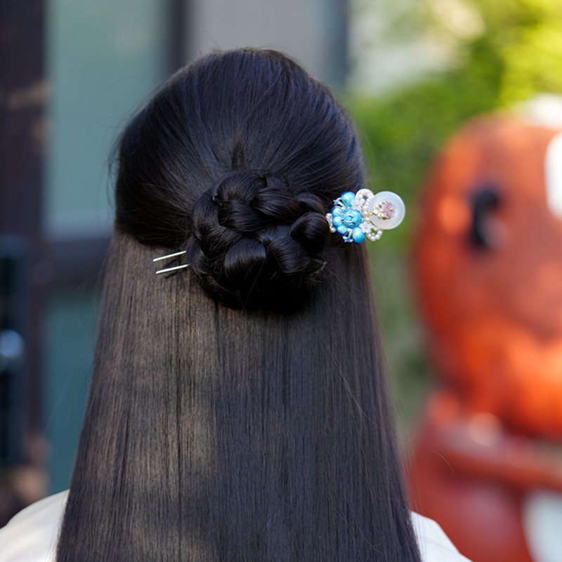 Hand-placed hair stick securing an elegant Hanfu-inspired bun, soft lighting