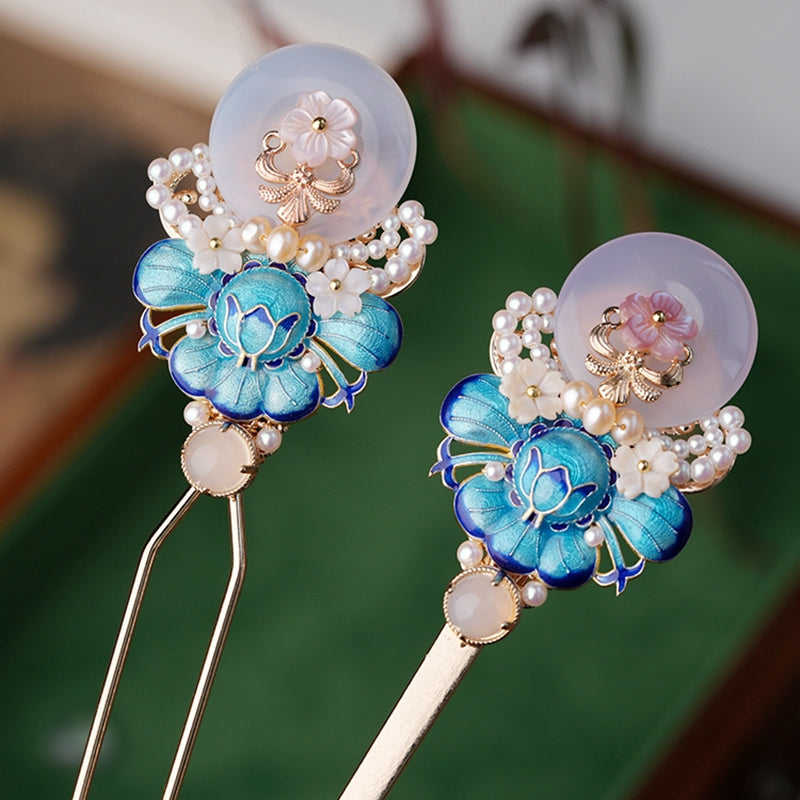 Close-up of jade-tone floral ornament resting in a low twisted bun
