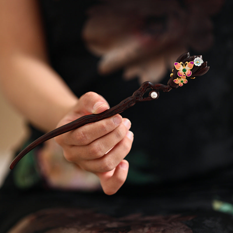 Dark wood stick with hand-painted pink flowers worn through a low bun