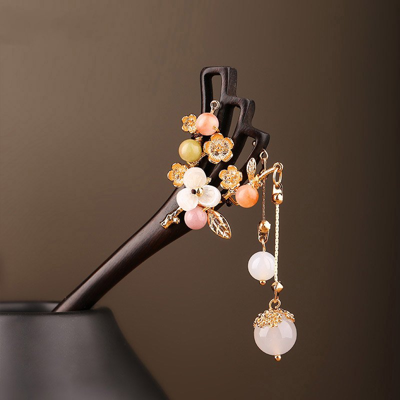 Dark wood-look stick with black tassel resting atop a neatly twisted bun