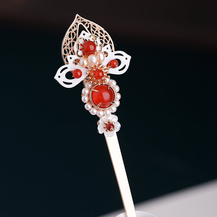 Warm wood-look hairpin with small floral cluster resting on satin fabric