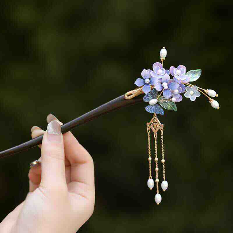 Lavender wisteria blossoms clustered atop a dark hair stick resting in a bun