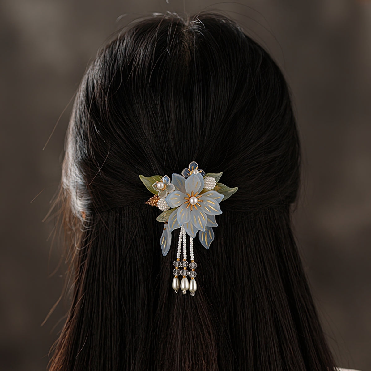 Delicate petal sprig in muted pink tones rests sideways on gathered hair, wedding accent