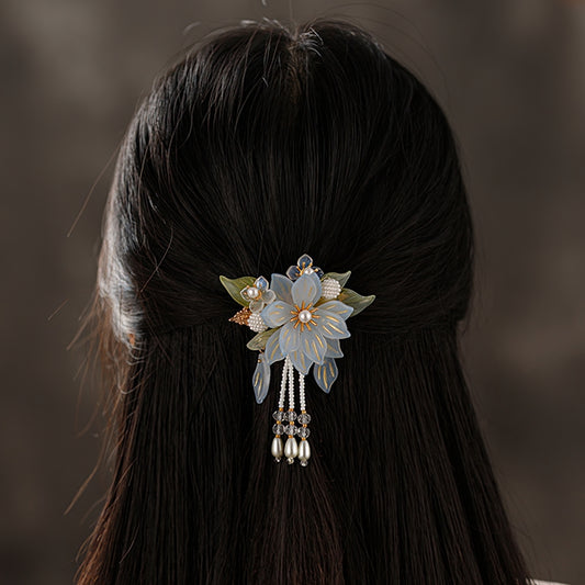 Delicate petal sprig in muted pink tones rests sideways on gathered hair, wedding accent