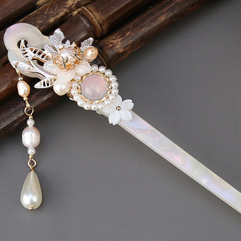 Dark wood-like stick with handpainted red and gold blossom tucked into a bun