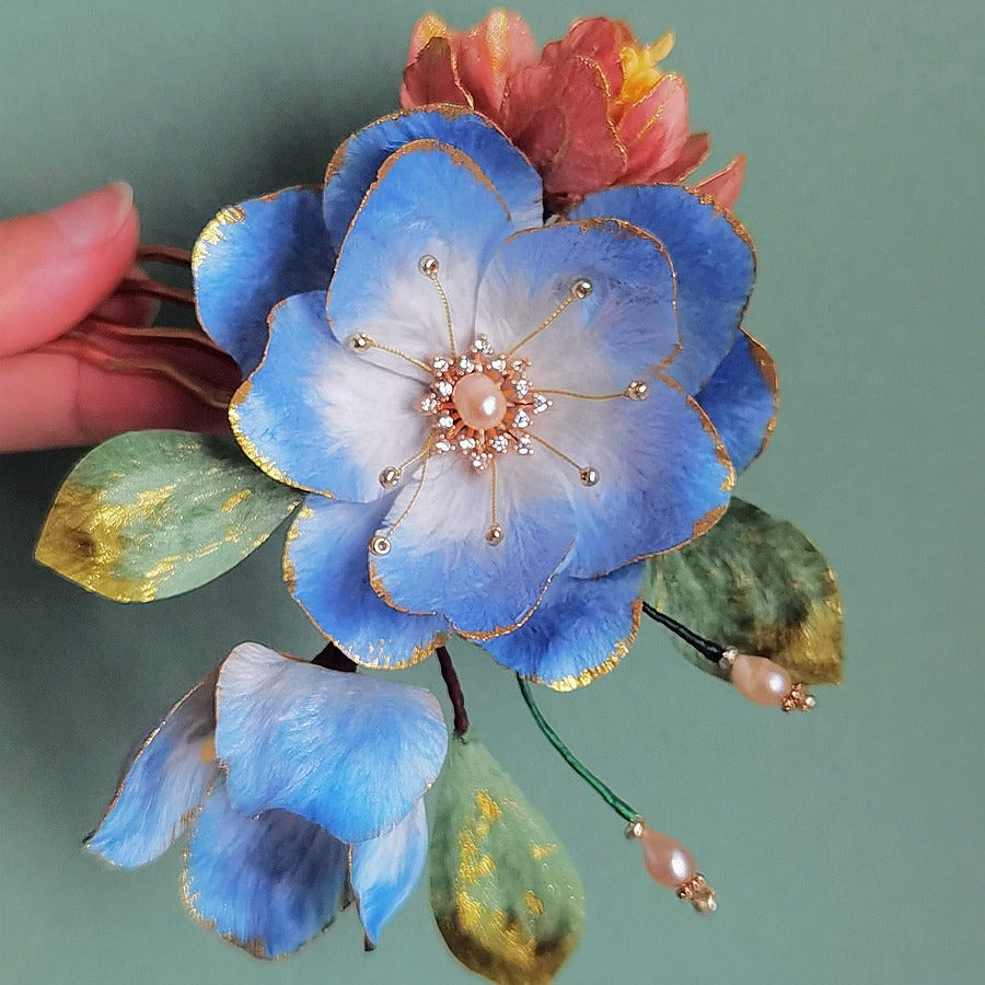 Soft blush flower clipped at the side of a low bun, carved petal detail visible.