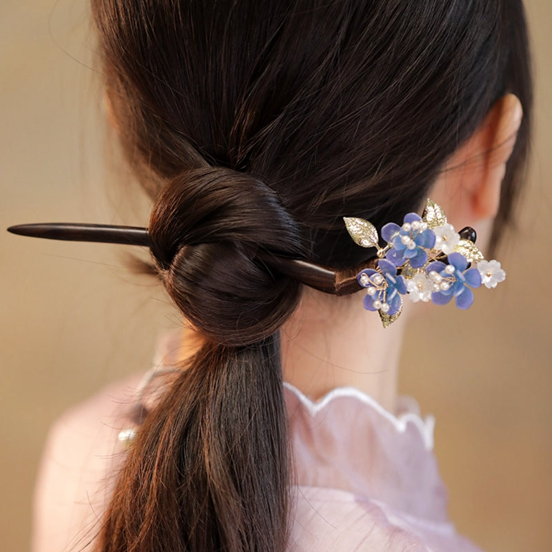 Close-up of carved blossom detail on smooth dark-wood hair stick