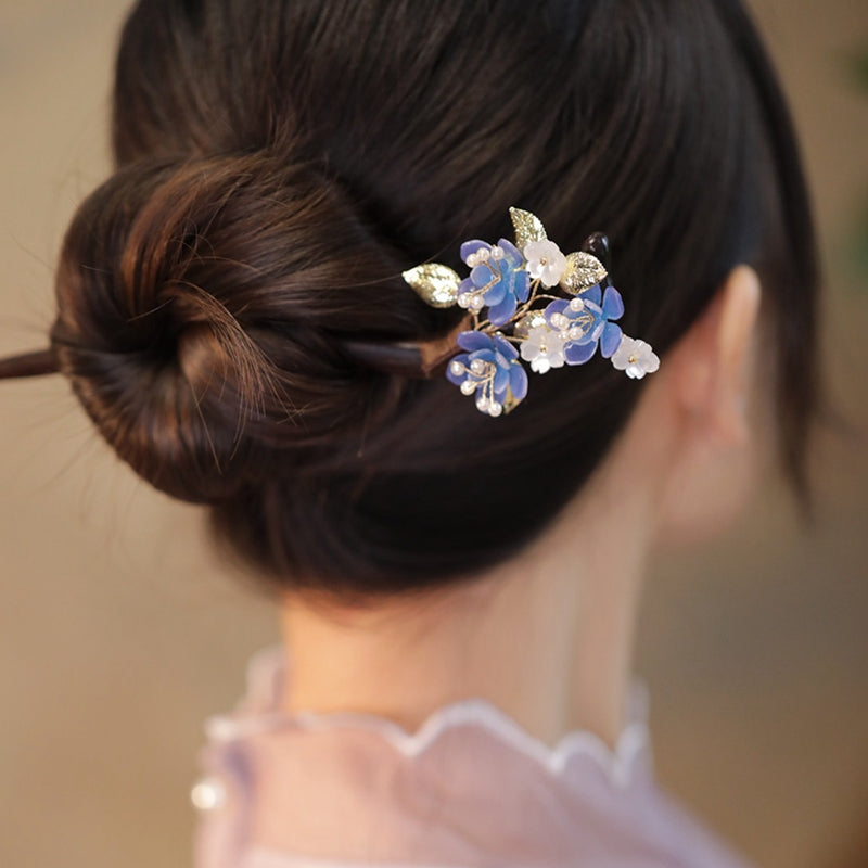 Two slim dark hair sticks crossed over a bun on mannequin