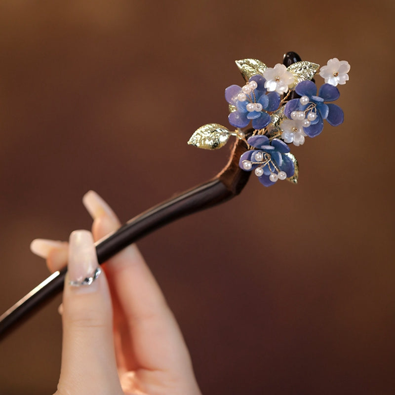 Dark wood hair stick with carved floral motif resting on folded linen