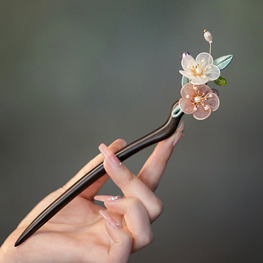 Dark sandalwood-look hair stick with carved floral tip holding a low bun