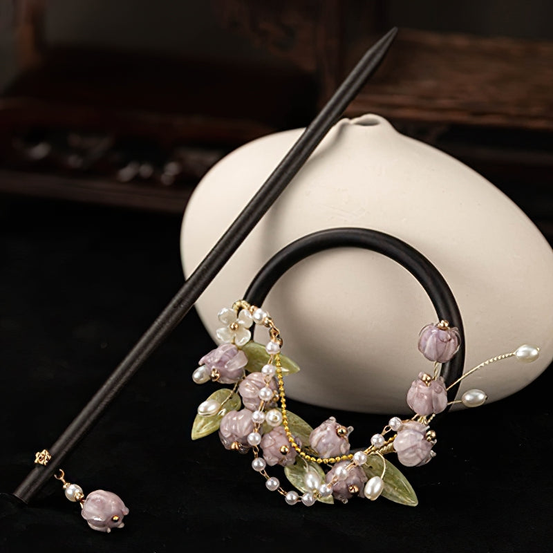 Dark wood hair stick resting across a low bun on brown hair
