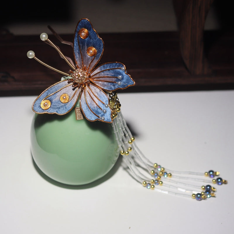 Close-up of blue motif on slender stick, worn in a low bun