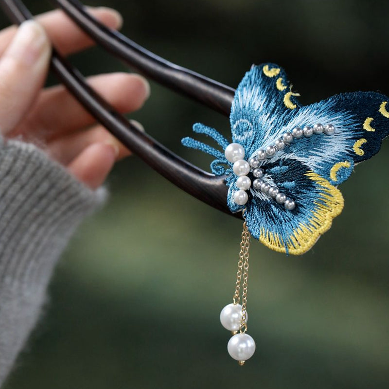 Close-up of small blue butterfly accent perched on curved pin, held in bun
