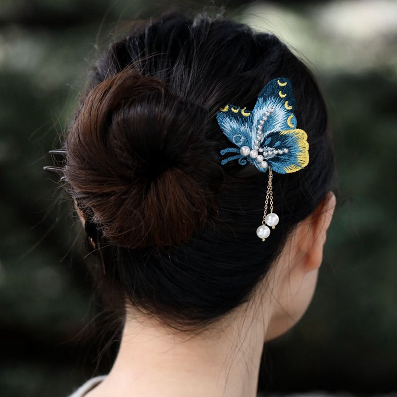 Side view of pin laid on fabric, showing delicate blue wings and profile