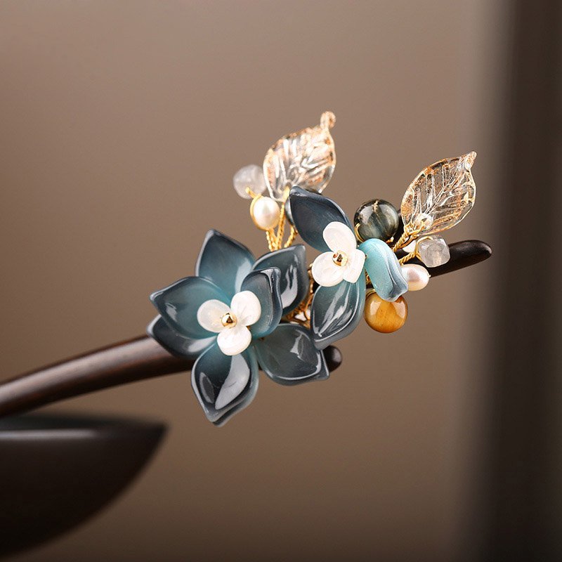 Close-up of blue flower ornament mounted on a slender wooden hair stick