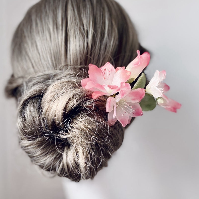 Model wearing the stick in a low bun, petals curving along the side