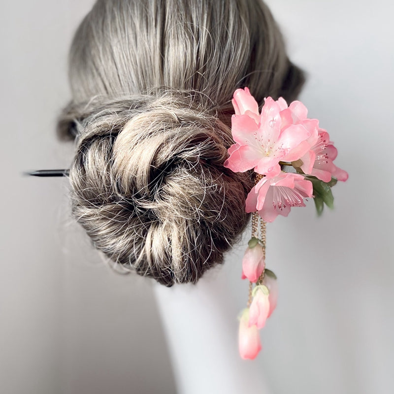 Close-up of floral cluster and slender pin, showing blush petals and gold accents