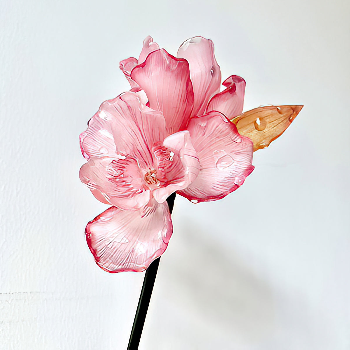 Slender hair stick laid flat featuring pink iris detail and curved end